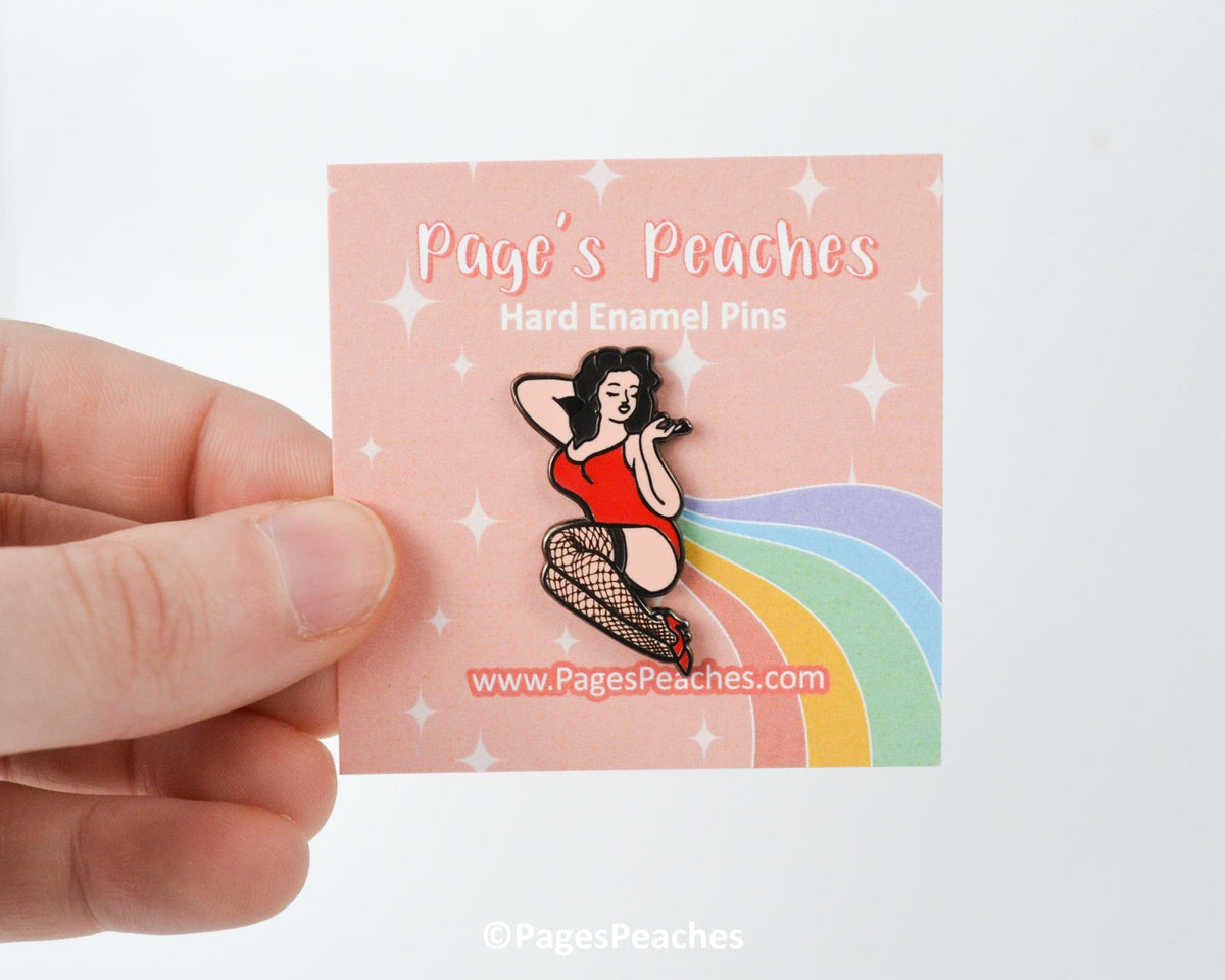 Pinup-style enamel pin designed by Page’s Peaches, featuring a femme figure in lingerie and fishnets.