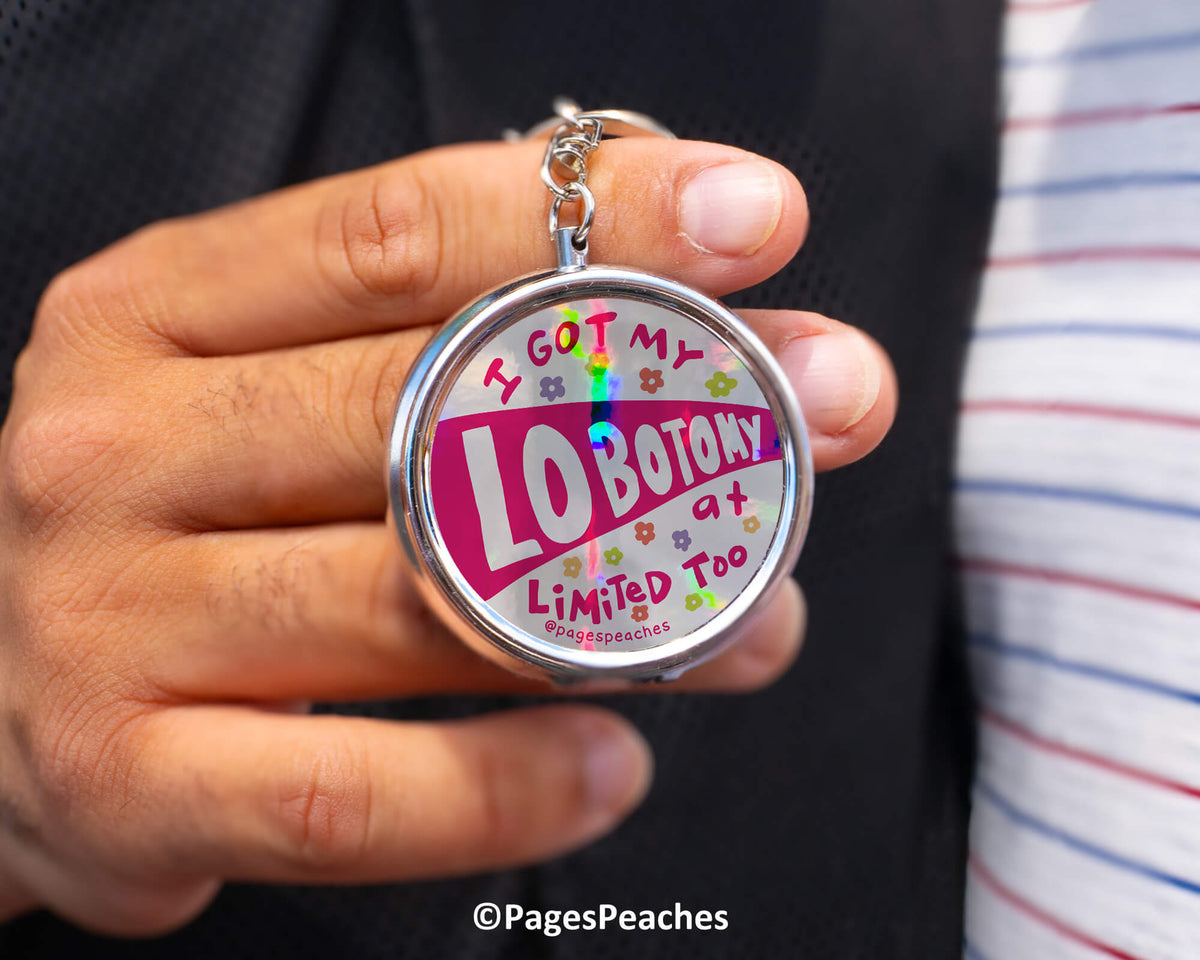 A person is holding a keychain with a colorful design featuring text and graphics.