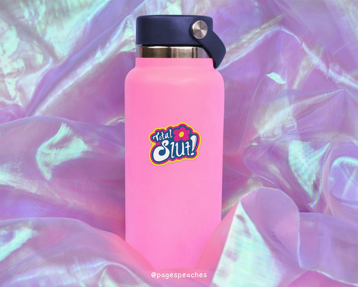 A pink water bottle with a black cap and a pink sticker with a cartoon character on it, placed on a purple fabric background.