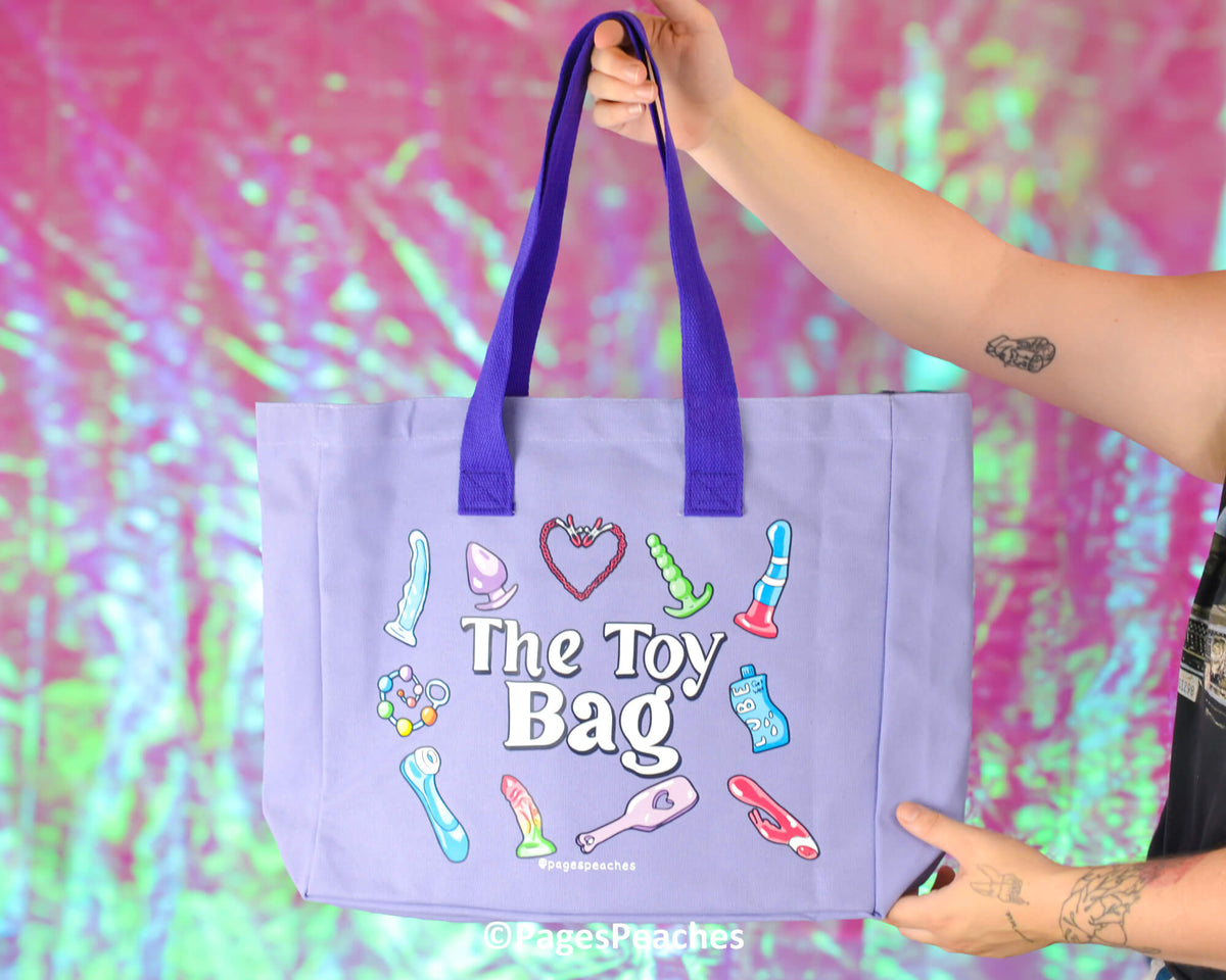 Purple tote bag with colorful illustrations and 'The Toy Bag' text, held against a vibrant, multicolored background.