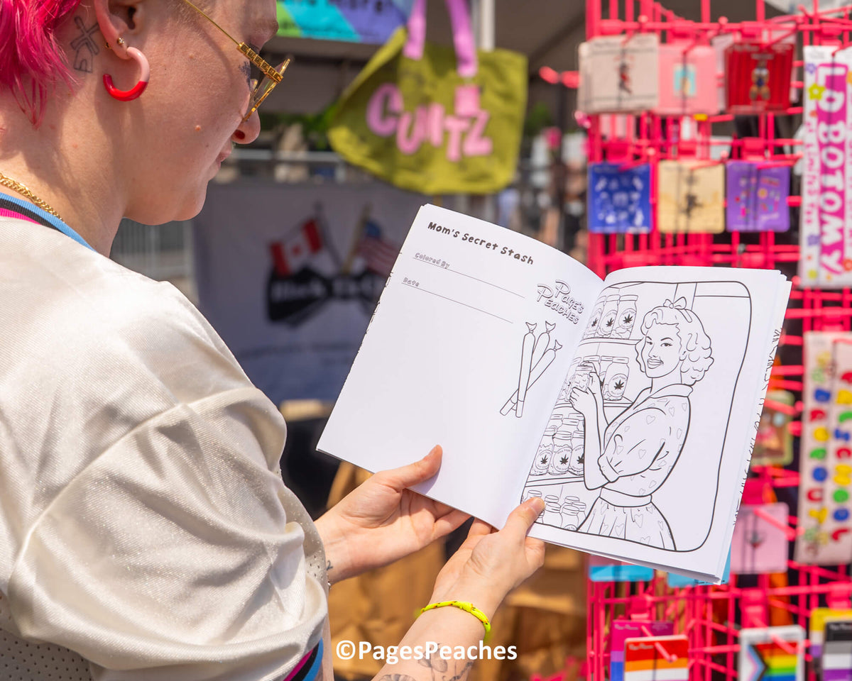 A person is holding a coloring book with a page titled "Mom's Secret stash" and an illustration of a woman. The person is looking at the book, which is placed on a table.