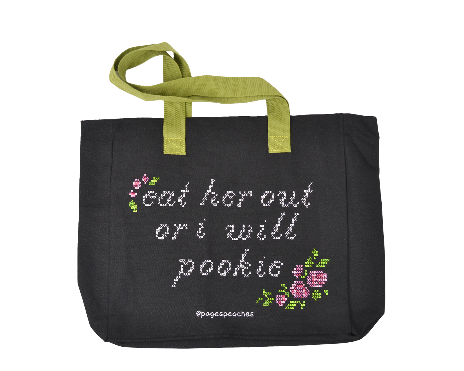 Black canvas tote bag with green straps and stitched-style text reading “Eat her out or I will pookie,” decorated with pink and purple pixel flowers
