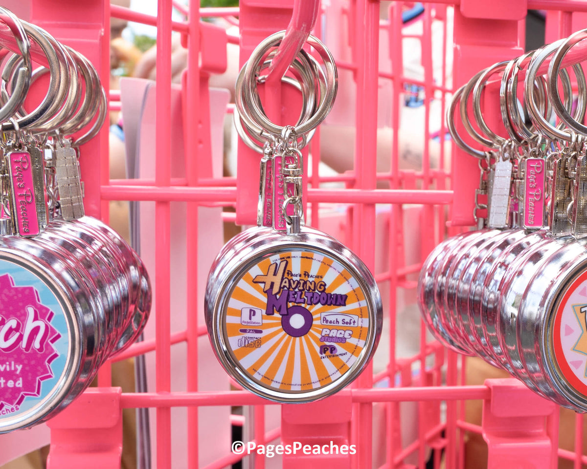a collection of keychains with various designs hanging on a pink metal structure.