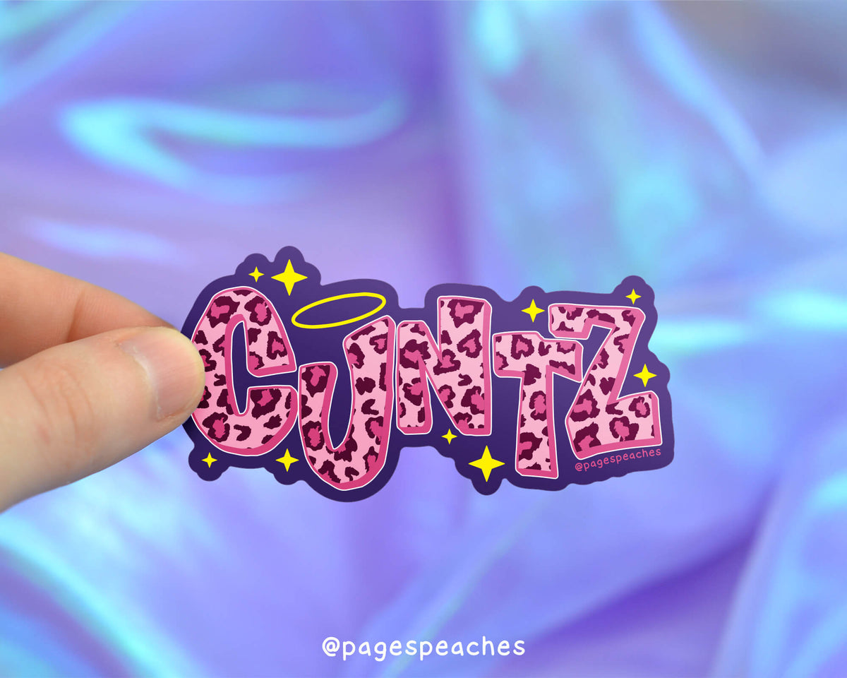 Sticker with 'CUNTZ' design held by a hand against a colorful background