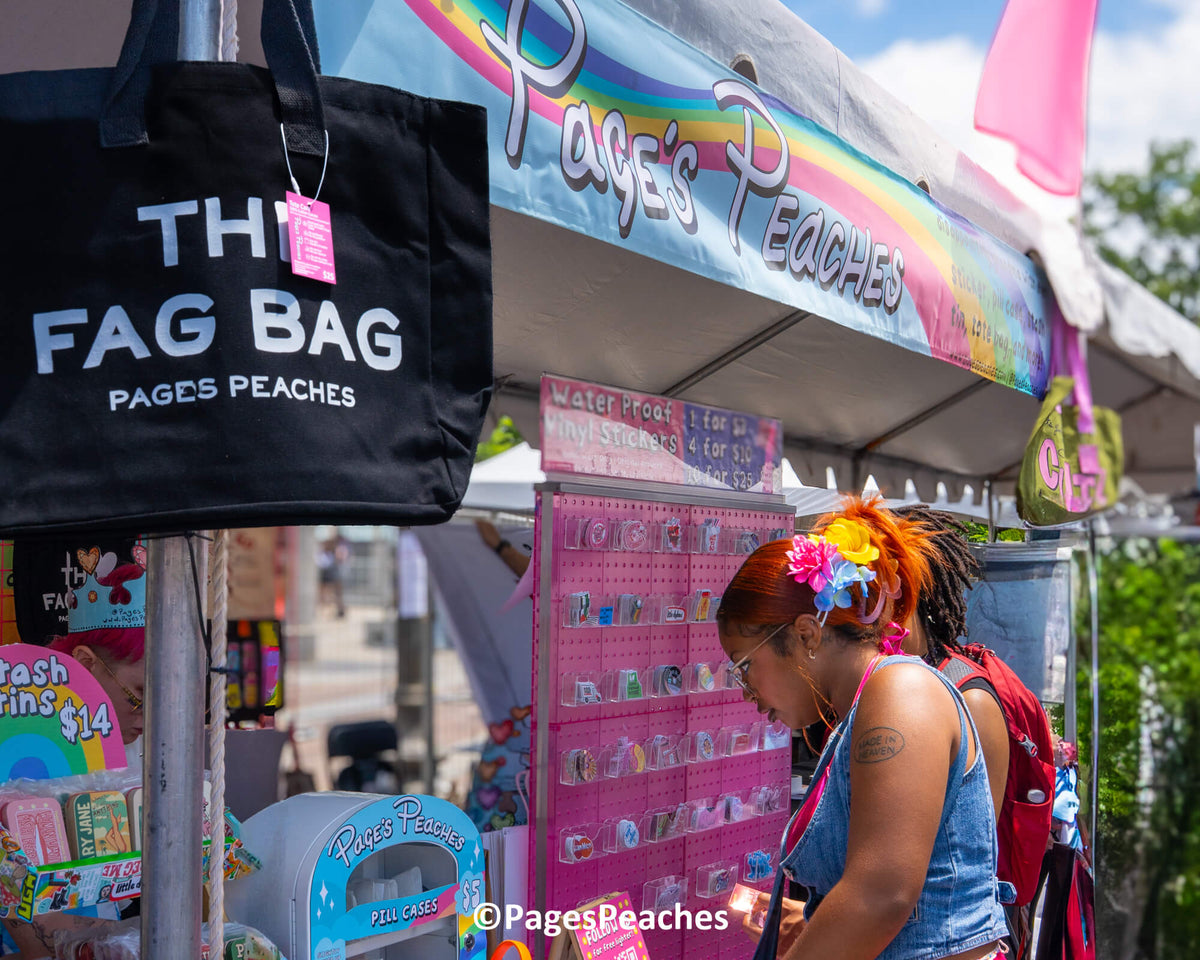 A woman with a flower in her hair is browsing items at a market stall, which is selling various products.