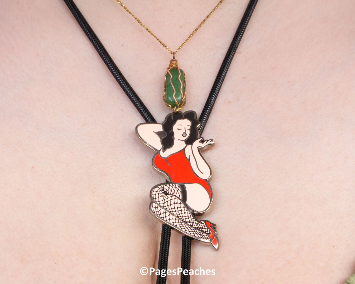 A close-up of a person wearing a necklace with a pendant featuring a cartoon-style illustration of a woman in a red dress and fishnet stockings.